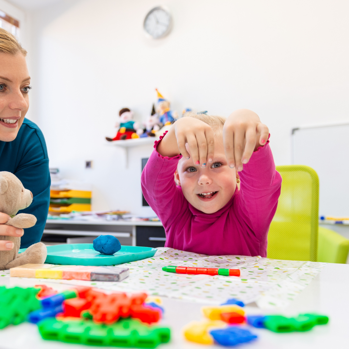 Pediatric occupational therapy session with a child playing with fine-motor manipulatives at a table while a clinician supports the activity.