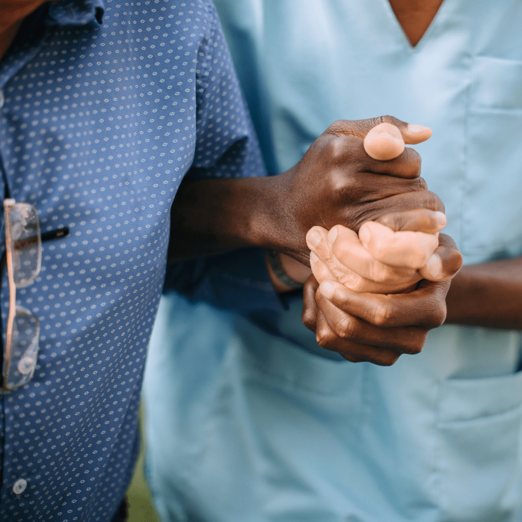 Two healthcare professionals in scrubs shaking hands in a medical setting.