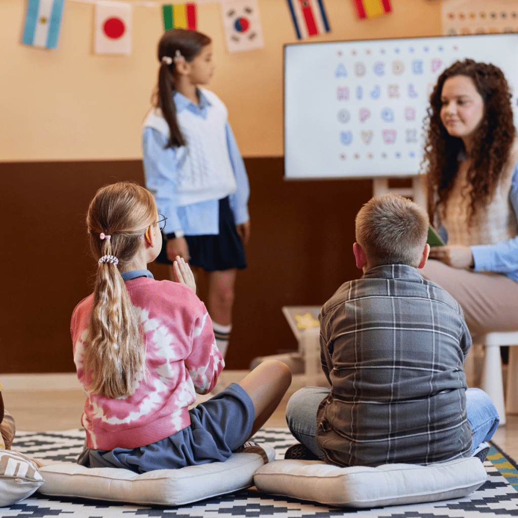 A smiling SLP professional working with elementary students in a classroom, highlighting the 15-18% projected growth in educational speech therapy roles. 