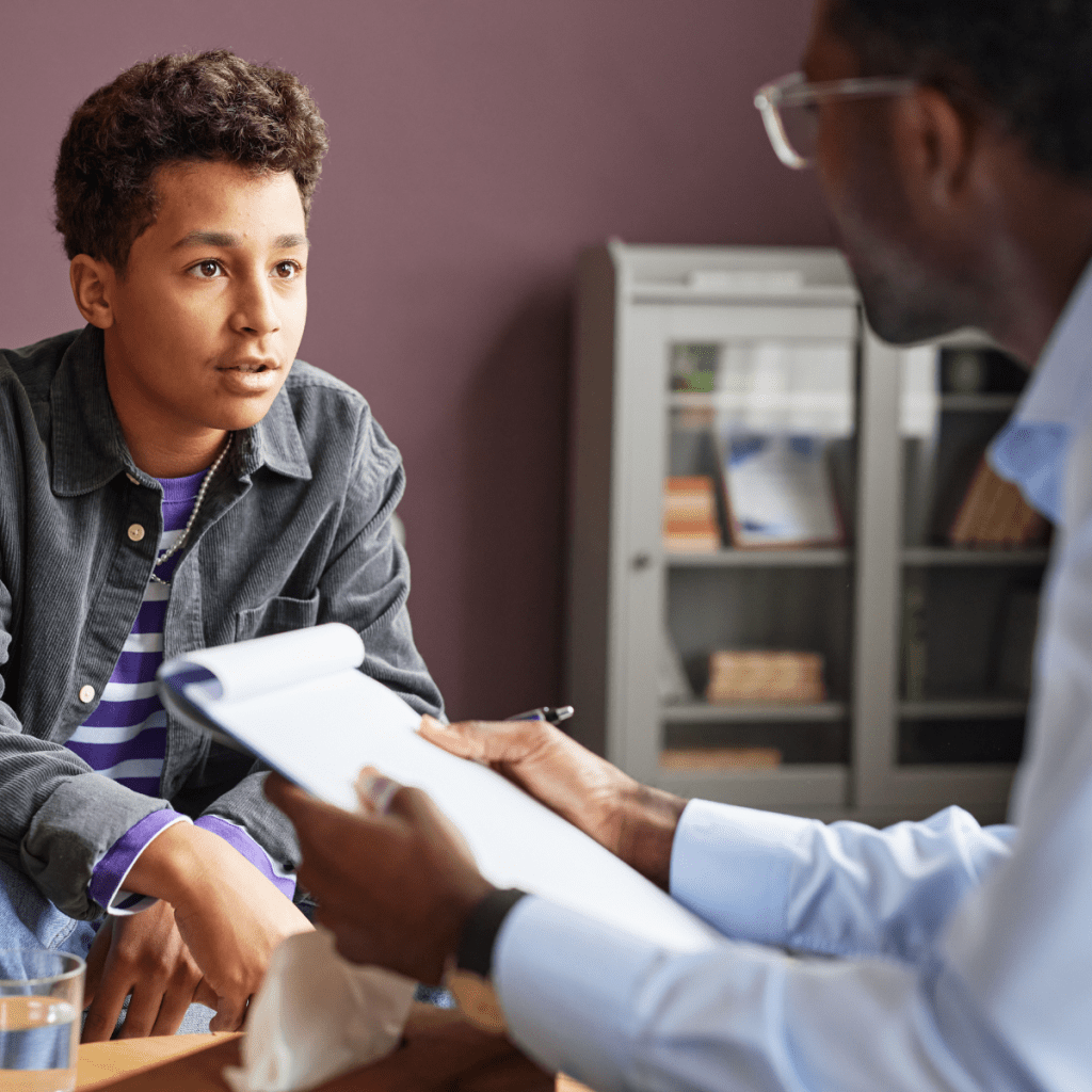 Clinical psychologist reviewing documents with teenage patient during a one-on-one psychological assessment session