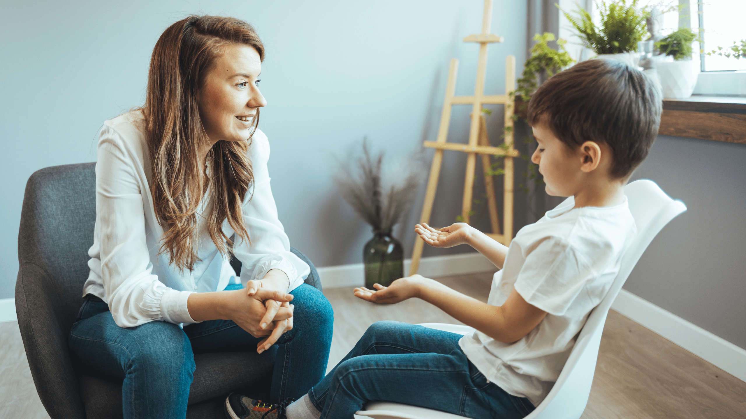Young boy having therapy with a child psychologist. Shot of a young child psychologist talking with a boy. Friendly young child psychologist talking with little boy suffering from emotional disorder in bright office.