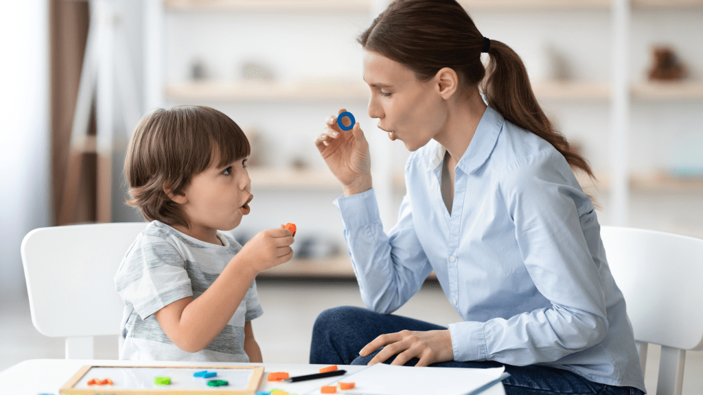 Speech language pathologist working with child on speech sounds using therapy tool during pediatric speech therapy session in clinical setting