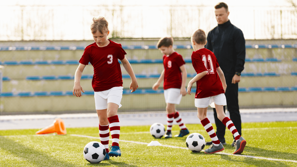 Soccer education for young boys. Physical education class for school children. Young coach with kids in team on training unit. Youth team coach training school boys in football soccer. 